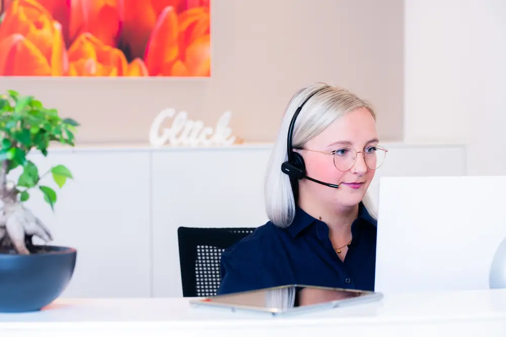 Empfangsdame sitzt mit einem Headset am PC